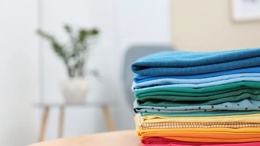 Different colored folded clothes on a table.
