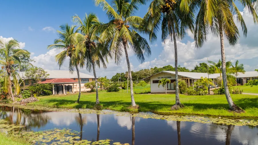 Water canal between former plantations in Suriname. School in the background.