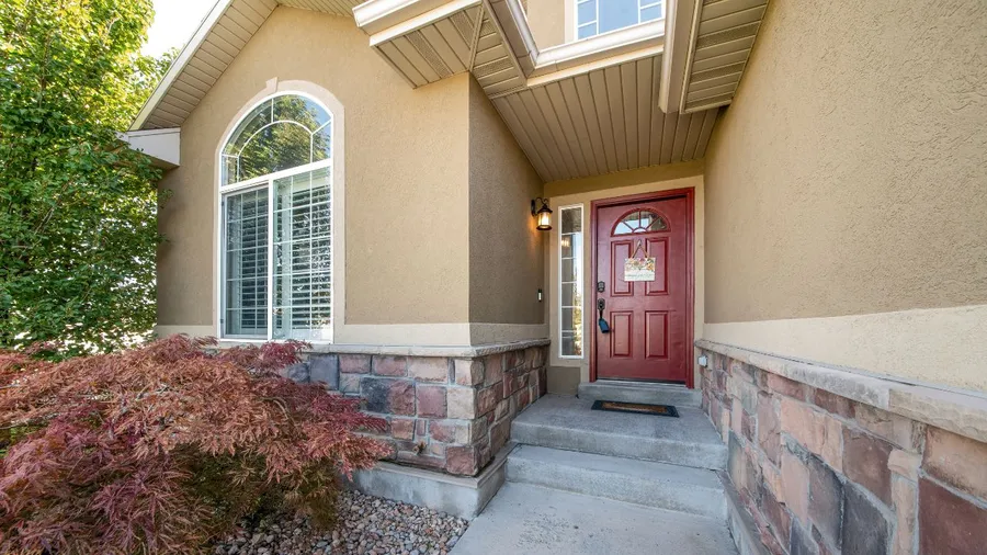 Bright house entrance with beige siding, stone accents, and vibrant red door.