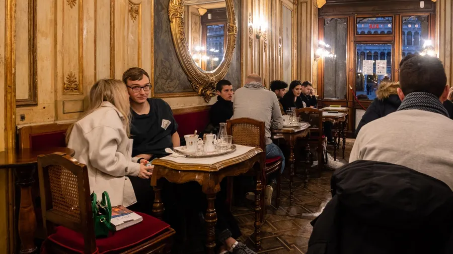 A warm, vintage-style café with wooden walls and red cushioned seats, filled with patrons.