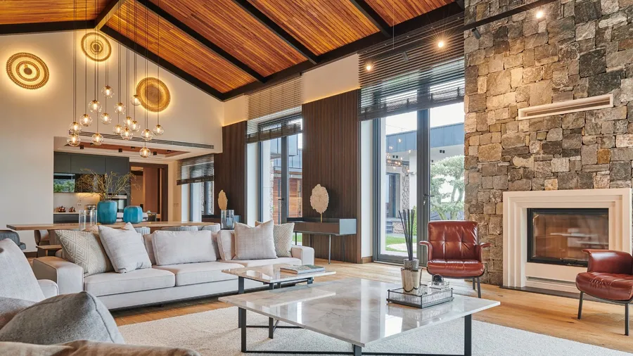 An open-concept living room with a vaulted wooden ceiling, large windows, and contemporary furniture.