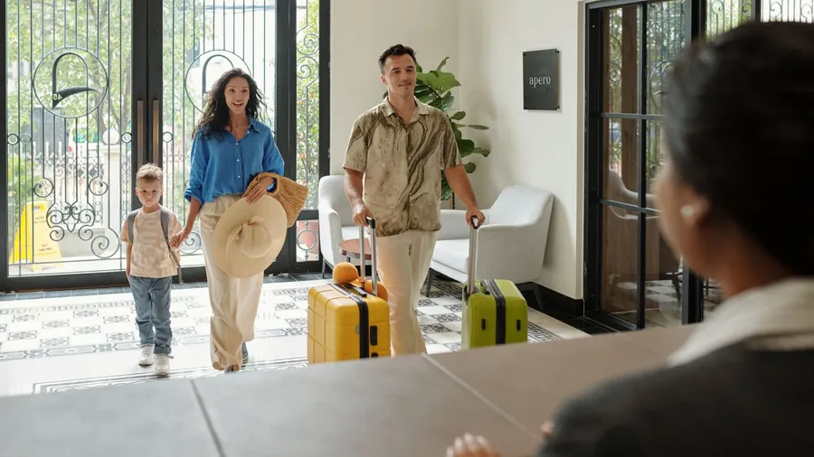 Family checking into hotel lobby with luggage.