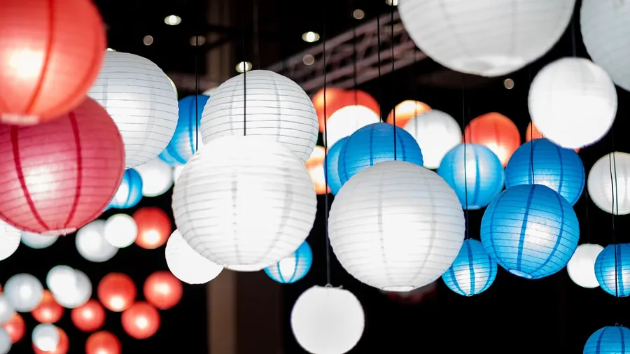 Paper lanterns in red, blue, and white hanging from a pergola.