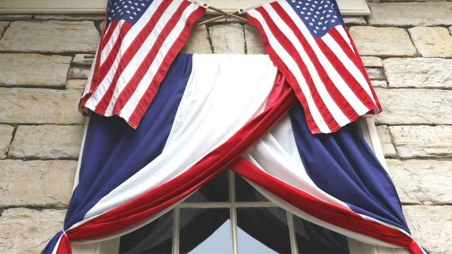 A decorated window for Memorial Day with American flags hanging over it.