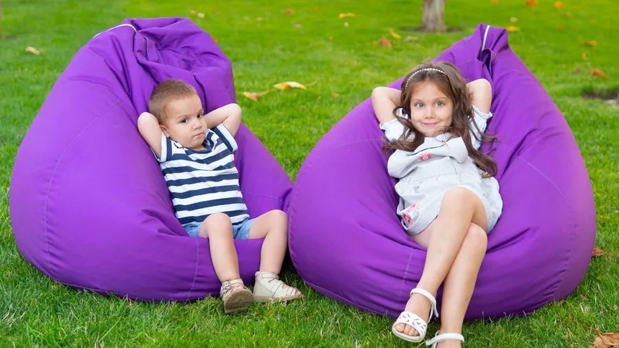 Two children lying down on purple bean bags.