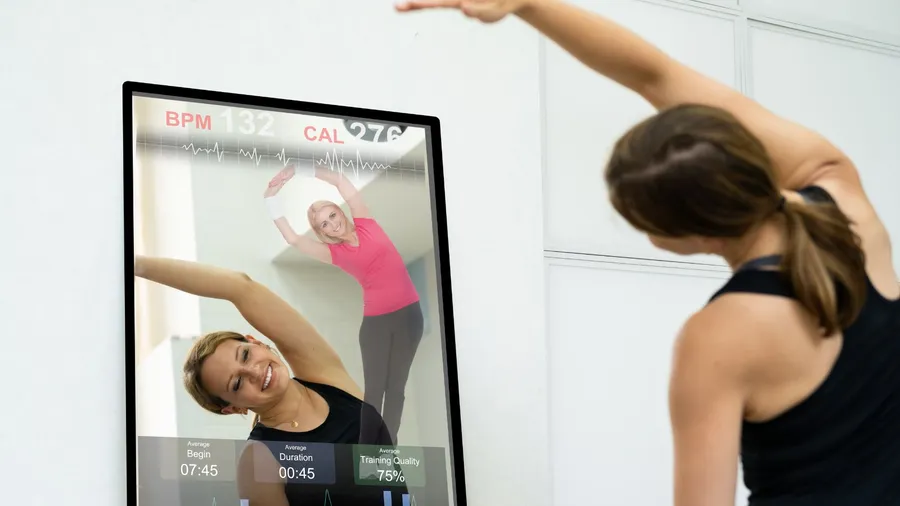 A woman stretching in front of a mirror displaying her workout stats.