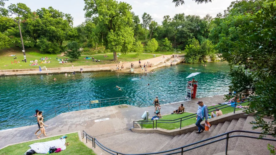 Tourists and swimmers enjoy the cool natural water of Barton Springs pool in Austin, Texas.