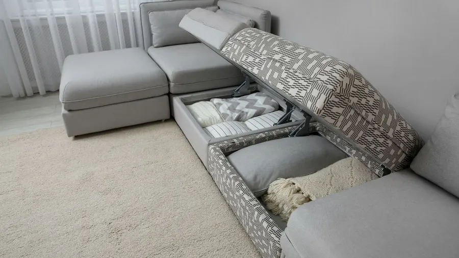 A sectional sofa with storage compartments under the seats, containing pillows and blankets
