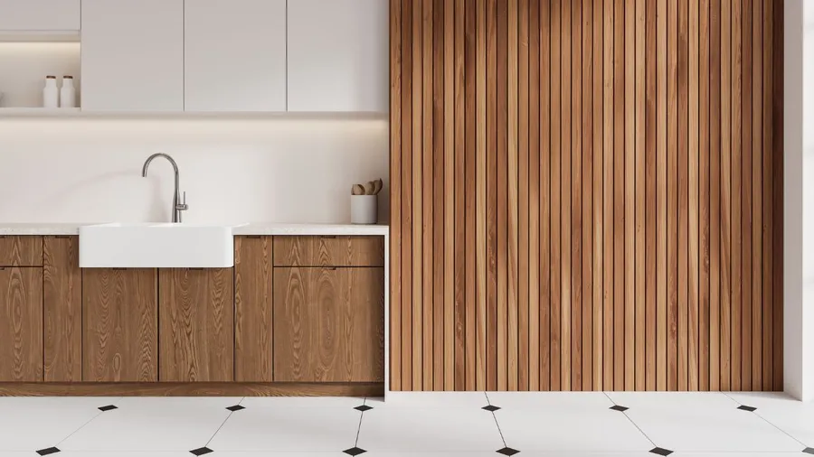 A modern kitchen with white cabinets, a white farmhouse sink, and wooden paneling on the wall.