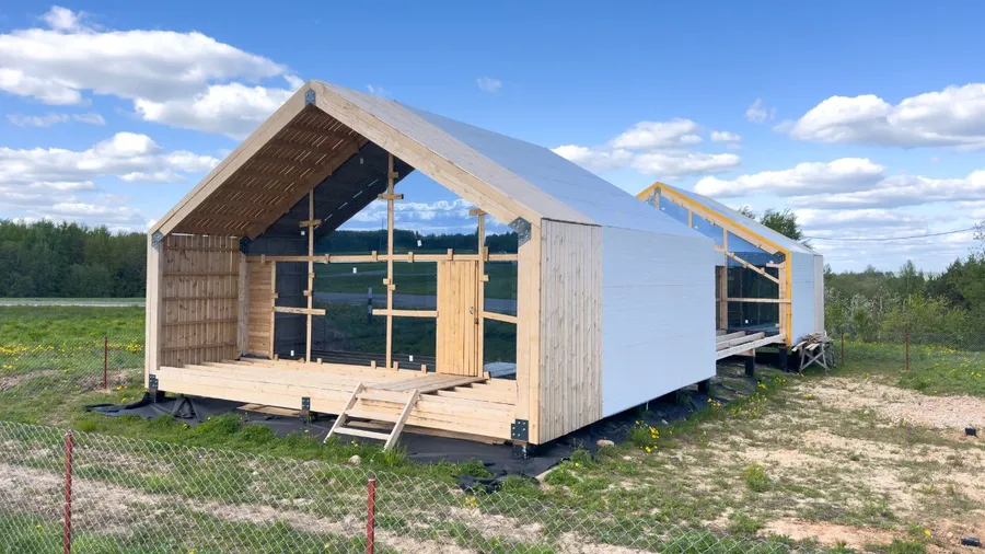 Wooden and barn under-construction shed with black and natural wood exterior on a grassy field.