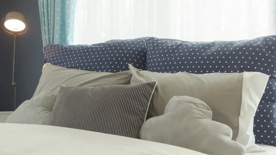 Blue polka dot style bedding with gray color pillows on bed