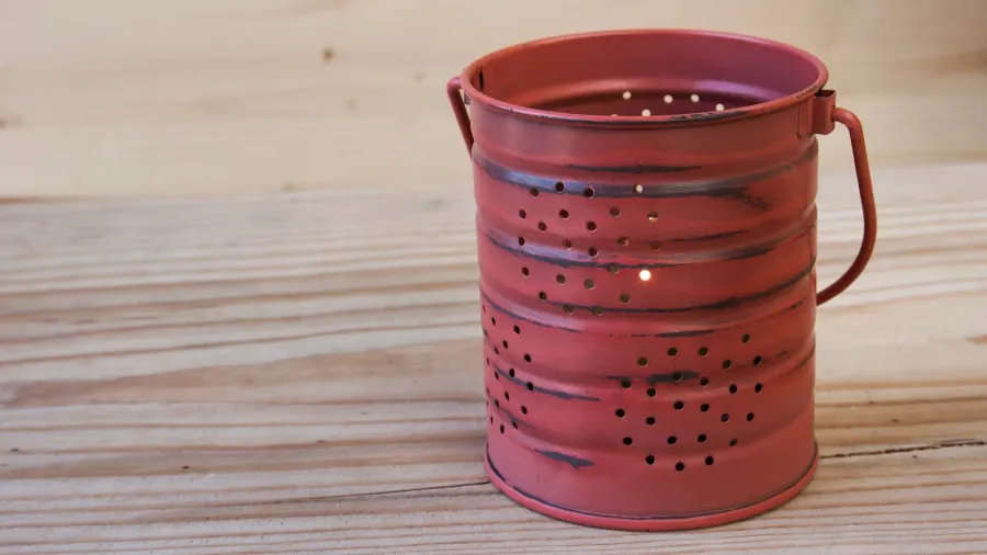 An upcycled tin can lantern on a wooden surface.