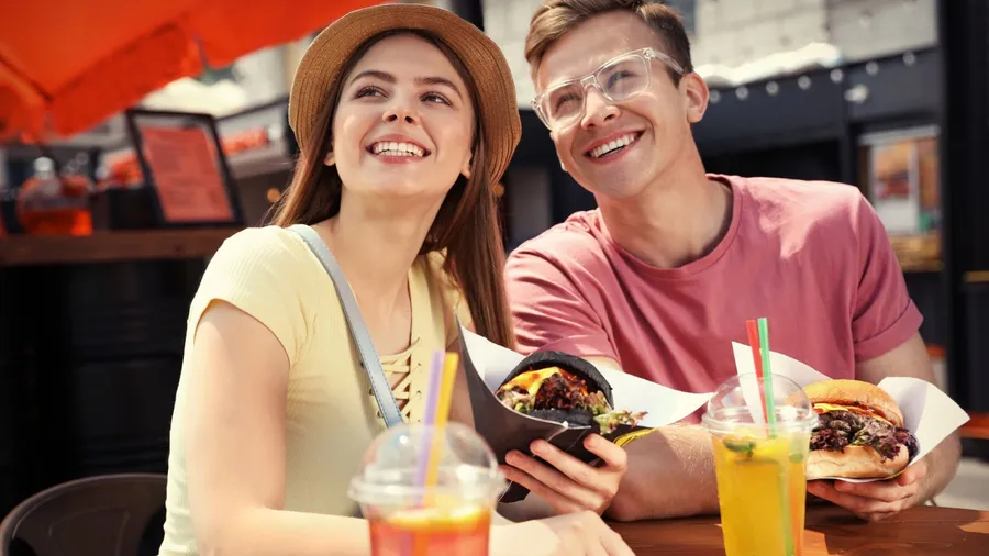 young happy couple with burgers in street cafe