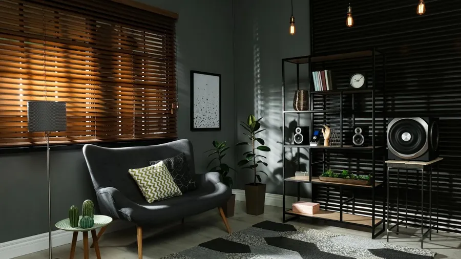A modern living room with a gray sofa, black shelving, and wooden accents.