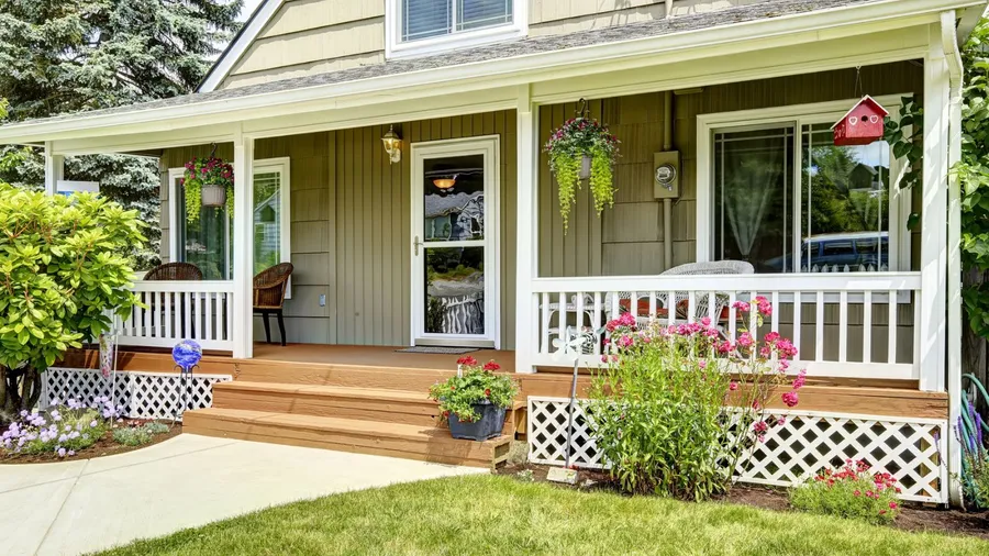 A cozy porch with chairs, flowers, and a birdhouse.