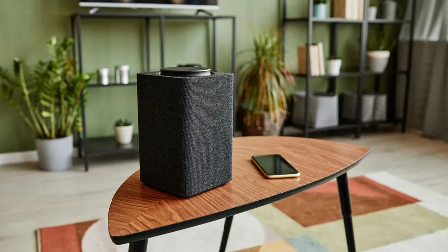 Close-up of a speaker and smartphone on a wooden coffee table.