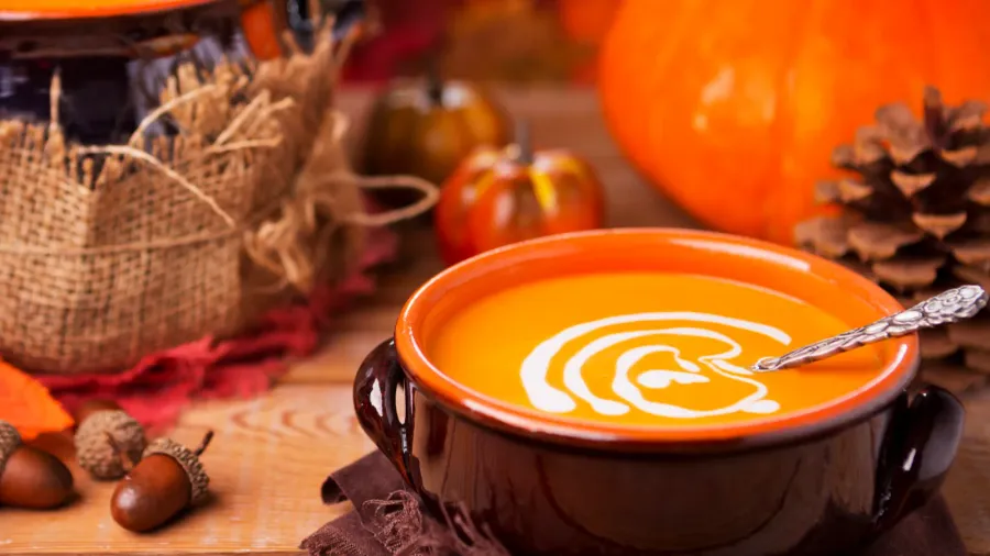 Homemade pumpkin soup on a rustic table with autumn decorations.