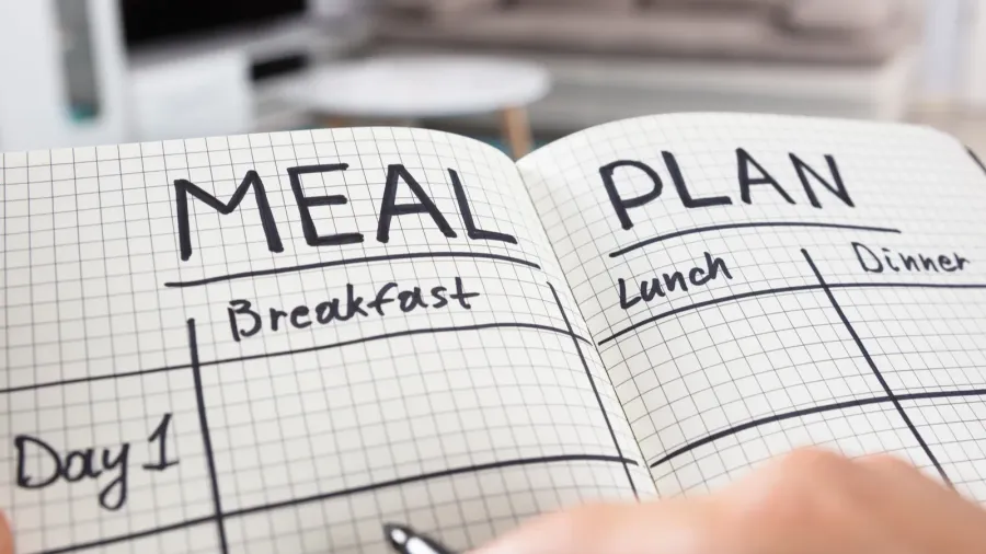 A person making a meal plan in their journal.