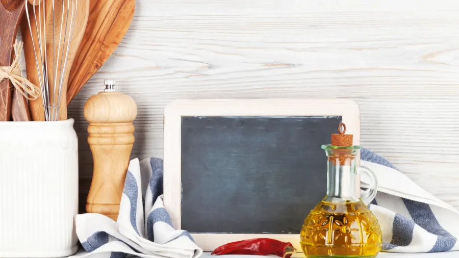 Kitchen utensils and chalkboard on a kitchen countertop.