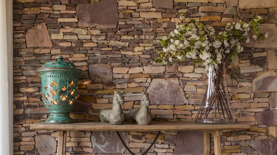 Living room with decorative table, stone wall behind.