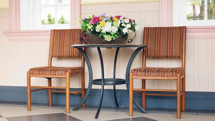 Two striped chairs beside a round table adorned with flowers.