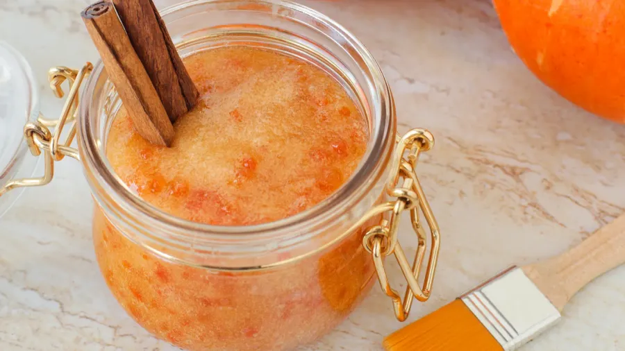 Pumpkin scrub with sugar and cinnamon in a glass jar. Homemade beauty treatment and spa recipe.