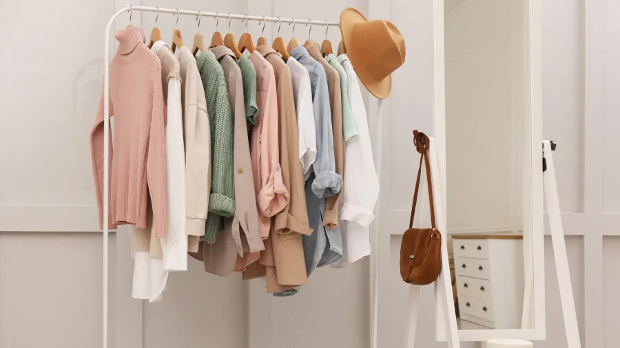 Rack with stylish women's clothes and mirror in dressing room.