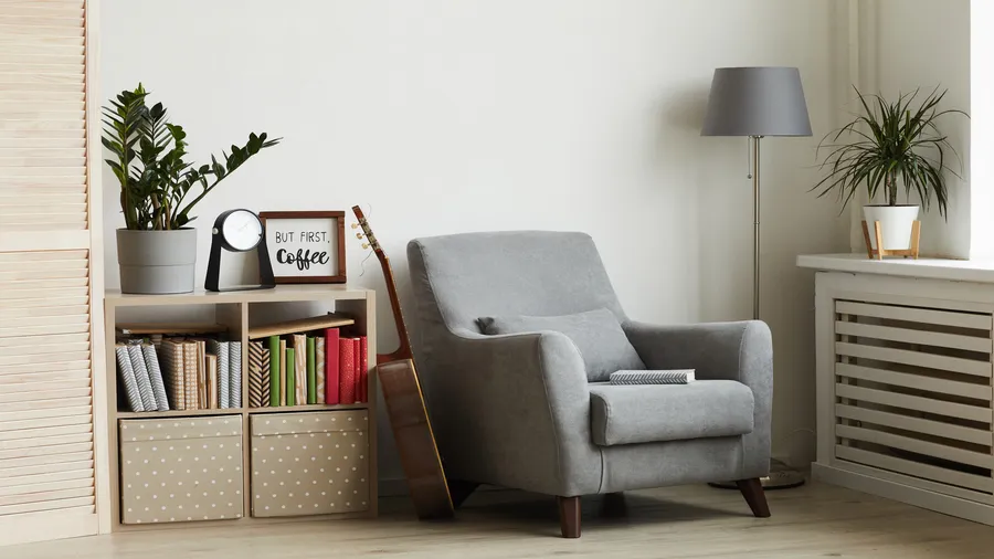Cozy living room corner with plants, books, a lamp, and a guitar, creating a relaxing atmosphere.