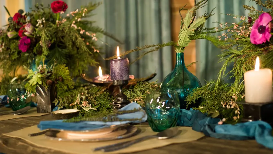 A table decorated with candles, floral arrangements, and elegant glassware for a cozy, festive atmosphere.