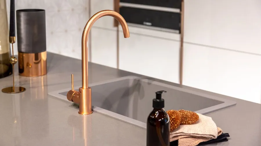 Kitchen sink with copper faucet and hand towel.