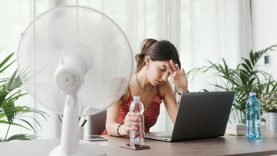 Woman working on a laptop with a headache, holding her forehead.