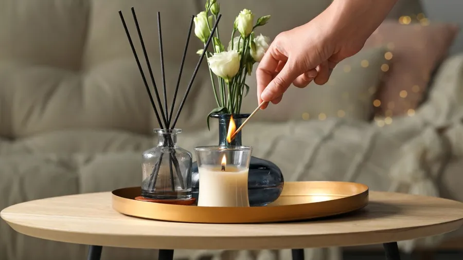 Hand placing a flower in a vase with candles and decorative items.