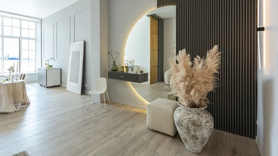 A contemporary living space with minimal decor, a large vase with dried flowers, and textured walls.