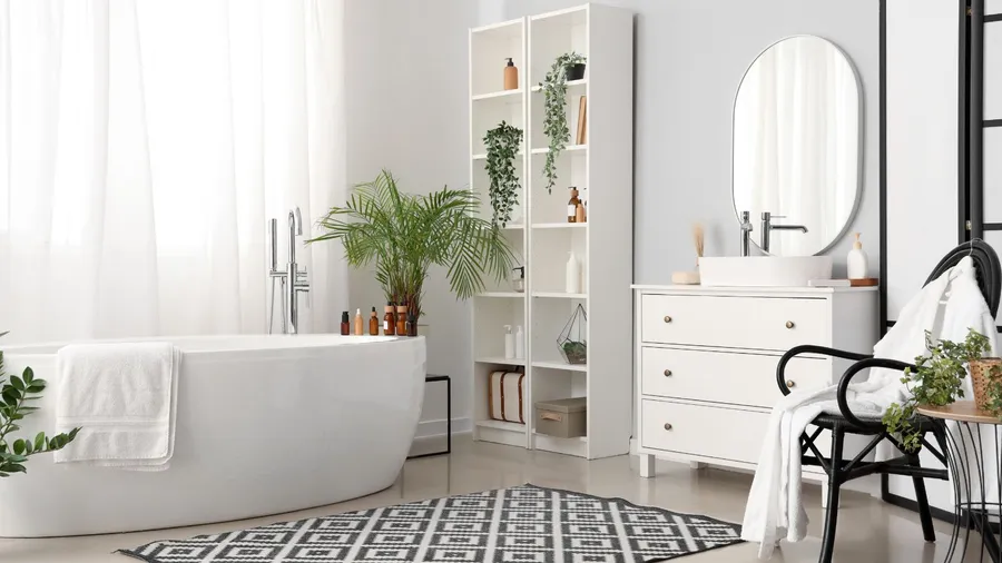 A minimalist bathroom featuring a white tub, plants, and a stylish shelving unit.