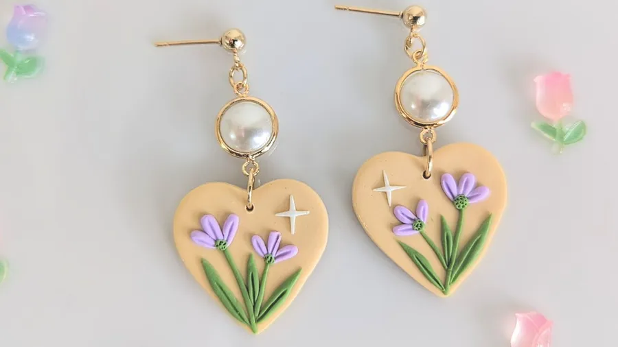 Heart-shaped earrings with purple flowers and green leaves design.