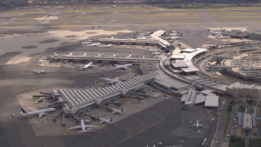 AERIAL, CLOSE UP: Flying above airplanes parked on apron waiting for passengers to board through jetway and start their traveling journey. Terminal building on New York Newark international airport