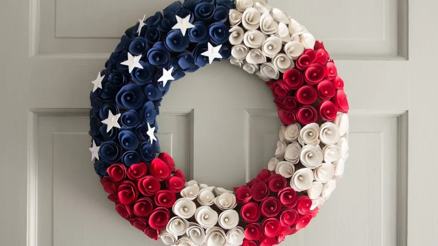 A DIY wreath made from paper roses and felt stars hanging on the door.