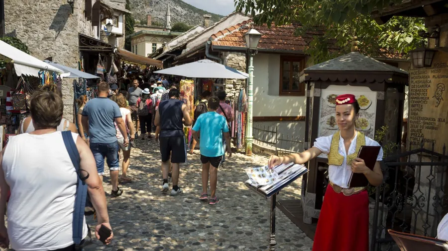 MOSTAR, BOSNIA AND HERZEGOVINA - AUGUST 05, 2015: A girl dressed in traditional costume invites tourists and locals to the restaurant