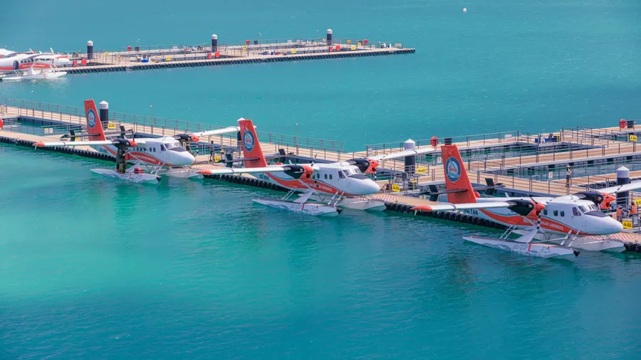 Maldives. Seaplane parking next to new floating dock in calm blue sea. Luxury travel transportation, exotic tourism. Taxing Trans Maldivian Airways Twin Otter seaplanes at Male airport (MLE) 15.03.23