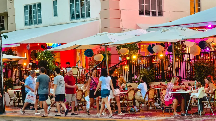 Miami Beach, Florida - July 8, 2024: Vibrant scene of people dining and walking at an outdoor restaurant on Ocean Drive in South Beach.