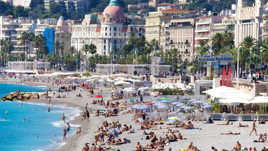 Nice, France - September 21, 2021: The long pebble Mediterranean shoreline in Nice, flanked by the historic Promenade des Anglais, is one of the most visited and iconic beaches on the French Riviera.