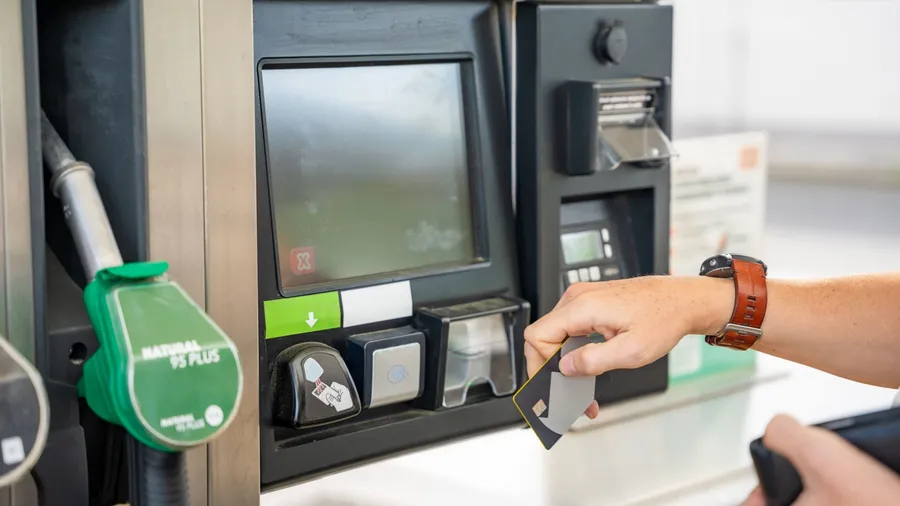 Close up view of man hand pays for fuel with a credit card on terminal of self-service filling station in Europe. High quality photo