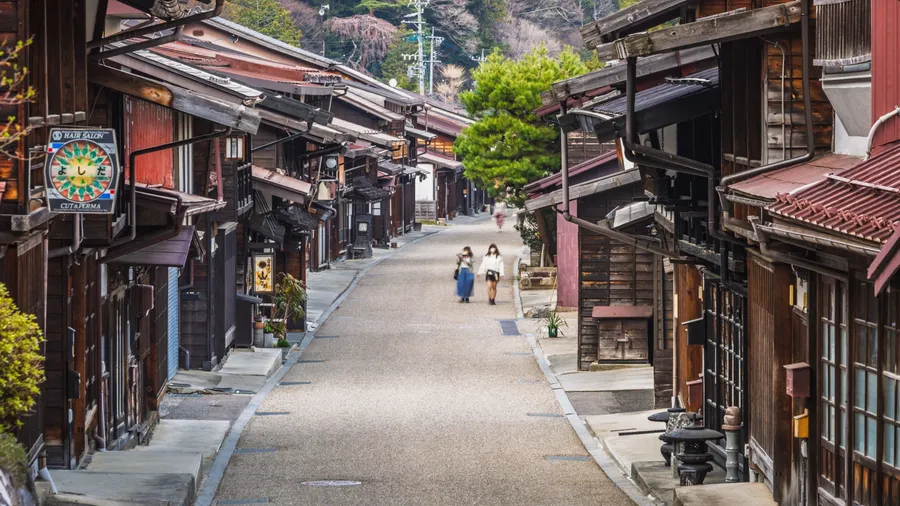 Narakawa, Japan - April 04 2023: Charming street in Narakawa, Japan, lined with traditional wooden houses. Two women stroll down the path, showcasing the serene atmosphere of this historic town.
