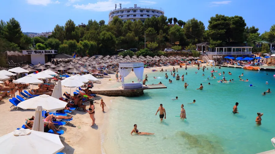 KSAMIL, ALBANIA - JULY 8, 2025: Tourists visit sandy beaches of Ksamil, mass tourism vacation resort town in Southern Albania.