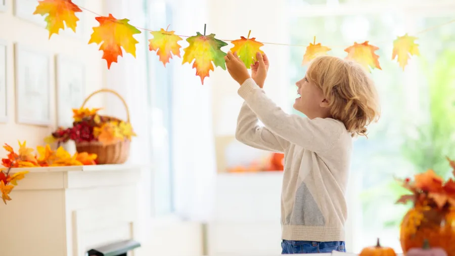 A child making a garland with leaves and a thread.