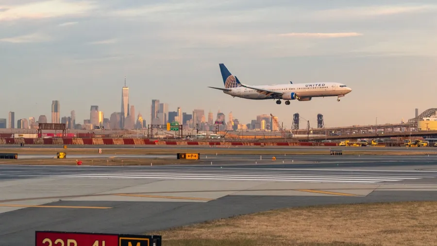 Newark Liberty Airport, Newark, New Jersey, USA - October 31, 2024 - United Airlines Jet landing at Newark Liberty Airport at golden hour with the Lower Manhattan skyline in the background