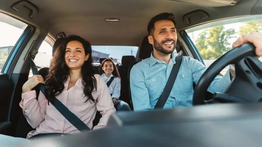 Happy european family of three riding car, traveling by automobile together, parents and daughter enjoying road trip on weekend, panorama