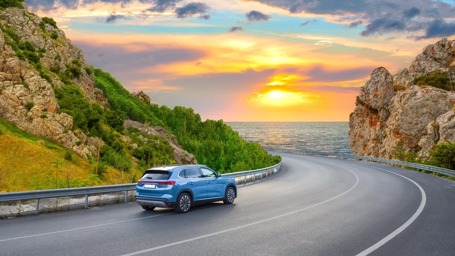 car driving on beautiful road in colorful sunset landscape in summer. Nature scenery on coastline highway. Europe travel trip in sea coast road landscape. summer vacation journey on road at the beach.