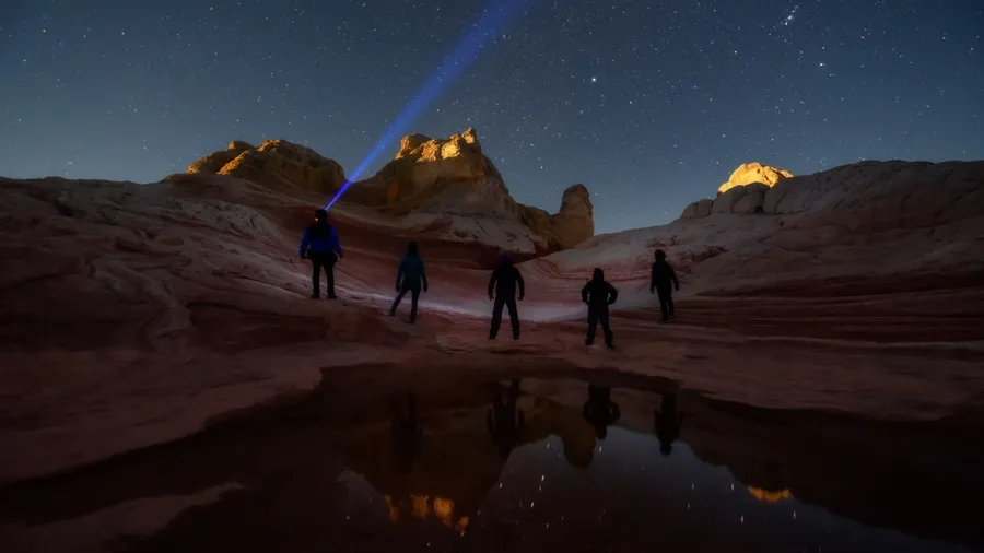 Group of stargazers posting under the night sky full of stars at White Pocket, remote area in Arizona desert. Inspring travel and adventure theme.