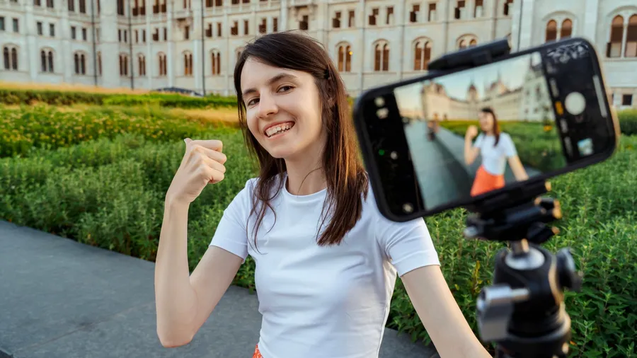 Happy Woman Filming Travel Vlog with Smartphone in Front of Landmark